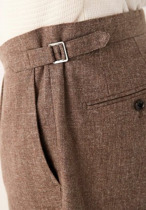 Brown tailored trousers made from textured fabric, featuring a silver buckle at the waist, pleats, and a back pocket with a button.