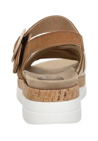 Braune Wildleder-Sandale mit Kork-Zwischensohle, weißer Gummi-Außensohle, Kreuzriemen-Design und einer dekorativen Schnalle am Riemen.