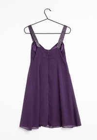 Lila klänning med en flödande kjol, satängmaterial och breda, glittriga band. Har en dragkedjestängning bak. Slät textur.