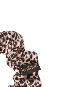 Haarband met luipaardprint gemaakt van soepel, zacht stof in roze en zwart, met een zwart label waarop in gouden tekst "le silque" staat.