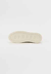 Semelle de chaussure avec surface texturée, en caoutchouc blanc, arborant les lettres "CPNHGN" et de petits motifs de bicyclette le long du bord.