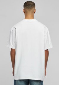 Tricou alb din bumbac, cu o croială lejeră, mâneci scurte și decolteu rotund. Textură fină, fără modele vizibile, design simplu.