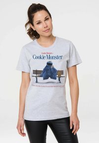 Gray cotton t-shirt featuring Cookie Monster graphic sitting on a bench, surrounded by cookie stacks. Text reads "Life is like a box of cookies."