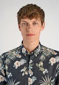 Camisa de manga corta abotonada en tela azul oscuro con un patrón floral que presenta hibiscus de colores claros y hojas tropicales.