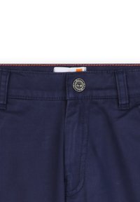 Navyblauwe katoenen broek met een metalen knoopsluiting, zichtbare stiksels en een label met een oranje accent. Soepele textuur en een op maat gemaakte pasvorm.