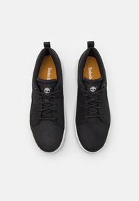 Melni sporta apavi ar gludu ādas un tekstila augšdaļu, ar saites aizdari, apaļu purngalu un gumijas zoli. Timberland logotips uz mēles.