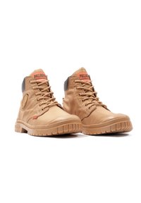 Tan waterproof boots with a high-top design, textured material, lace closures, a rubber sole, and prominent branding on the tongue.