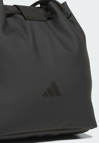 Czarna torba na ściągacz wykonana z gładkiego, matowego materiału. Posiada subtelne, wytłoczone logo oraz smukły design bez widocznych metalowych elementów.