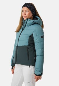 Himmelblauer und dunkelgrüner Steppjacke mit Kapuze, Reißverschluss vorne und Reißverschlusstaschen. Verfügt über eine gesteppten Textur und kontrastierende Farben.