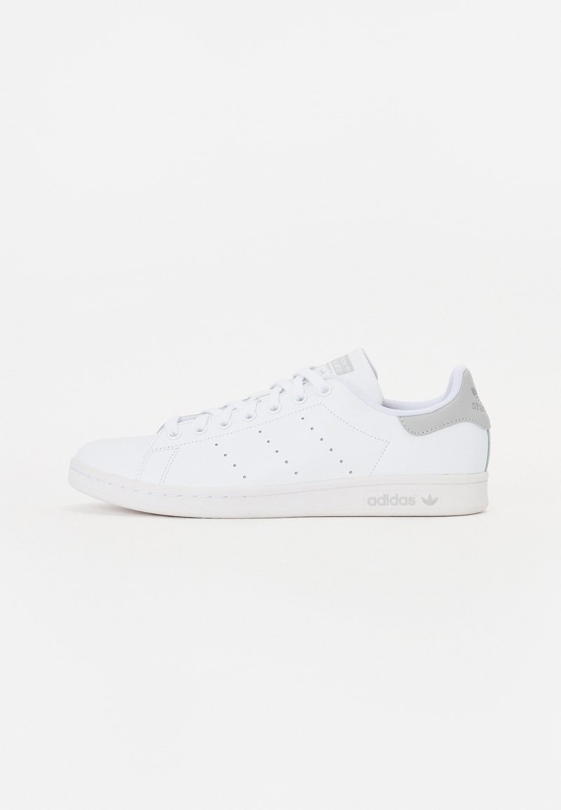 Hvide lædersneakers med en glat tekstur, perforerede detaljer på siden og lysegrå accenter ved hælen og tungen.