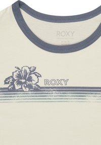 Helle beige T-Shirt mit einem marineblauen Rundhalsausschnitt. Mit einem Grafikdruck einer Hibiskusblume und einem gestreiften Muster in Blautönen. Markenname "ROXY" aufgedruckt.