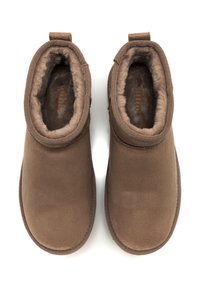 Stivaletti in suede marrone con fodera in pelliccia, punta arrotondata e linguette sul retro. Presentano cuciture a contrasto lungo i bordi.