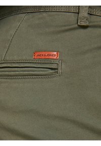 Oliwkowe spodnie o gładkiej strukturze, z tylnią kieszenią oraz brązową skórzaną metką wytłoczoną z napisem "JACK & JONES".