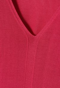 Fuchsia Strickstoff mit V-Ausschnitt, der eine glatte Textur und subtile Rippakzente entlang des Ausschnitts und der Mittelnaht aufweist.