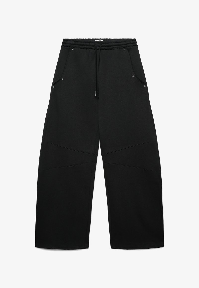 Pantaloni di tuta neri con vita elasticizzata, coulisse e quattro tasche. Presentano un tessuto testurizzato e dettagli di cucitura unici sulle gambe.