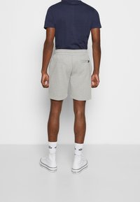 Shorts gris en tissu doux avec une taille élastique, associés à un t-shirt bleu marine et des baskets montantes blanches. Design simple et coupe décontractée.