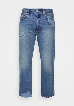 Jeans in denim blu con un taglio dritto, caratterizzati da un evidente effetto vissuto e dettagli in patch sulle tasche, una leggera sbiaditura e accessori in rame.