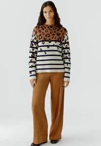 Gebreide trui met een bruin luipaardpatroon bovenaan en een body met witte en marineblauwe strepen. Gecombineerd met een brede bruine corduroy broek.
