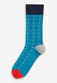 Türkise Socke mit einem marineblauen gerippten Bund. Verfügt über mehrfarbige Punkte und eine graue Ferse, ergänzt durch eine rote Zehenkappe.
