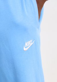 Svetlomodré bavlnené športové oblečenie s malým bielym logom Nike na boku, hladká textúra a jednoduchý dizajn.