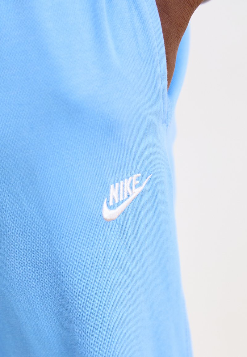 Ropa deportiva de algodón azul claro con un pequeño logo blanco de Nike en el lateral, textura suave y diseño sencillo.