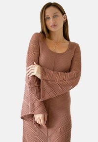 Długie rękawy, rdzawoczerwona dzianinowa sukienka o zygzakowatej fakturze, z rozszerzanymi rękawami i okrągłym dekoltem.