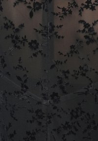 Țesătură neagră transparentă cu un model de catifea floral, având flori și frunze negre texturate, formă structurată cu detalii de cusătură.