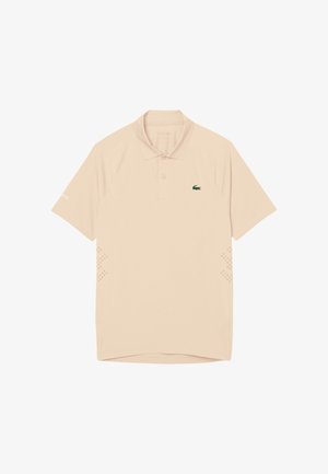 Polo beige à manches courtes avec col, patte à deux boutons, logo crocodile Lacoste sur le côté gauche de la poitrine et petits détails perforés sur les côtés.