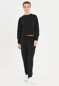 Zwarte cropped sweatshirt en bijpassende joggers van zachte stof, met een ontspannen pasvorm, lange mouwen, elastische tailleband en zijzakken.