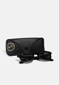 Gafas de sol Ray-Ban negras con lentes oscuros, forma rectangular, detalles en plata, acompañadas de un estuche negro texturizado con un logo.