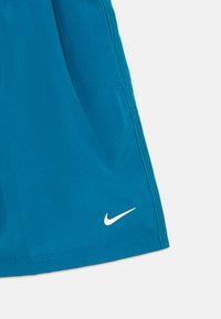 Sinised sportlikud lühikesed püksid, mille äärel on valge Nike swoosh logo ja tekstureeritud külgõmblused valgel taustal.