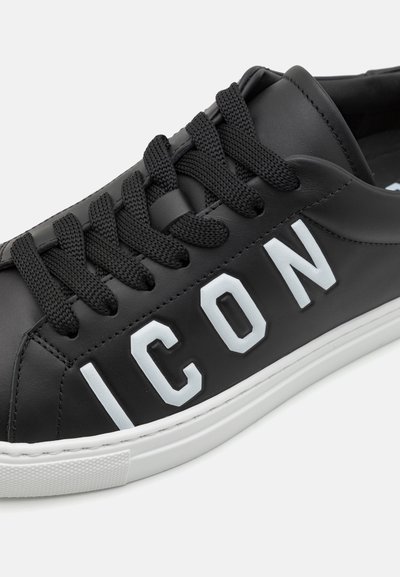 Musthave musta nahast toss, millel on mustad paelad, ja küljes on valge "ICON" logo ning tekstuuriga valge kummitald.