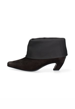 Botte cheville en suède noir avec un haut en tissu texturé doux, présentant un bout pointu et un petit talon incliné. Détails en motif crocodile sur le haut.