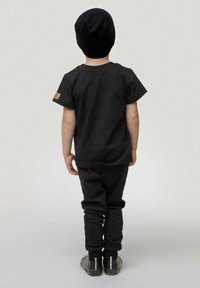 Completo per bambini neri composto da una maglietta a maniche corte e pantaloni tapered, entrambi di colore uniforme, completato da un berretto nero.