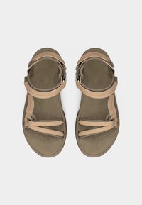 Ζευγάρι καφέ υπαίθρια σανδάλια με ρυθμιζόμενους ιμάντες, επίπεδες σόλες και αναπαυτικά πέλματα, σε άνω όψη πάνω σε ανοιχτό φόντο.