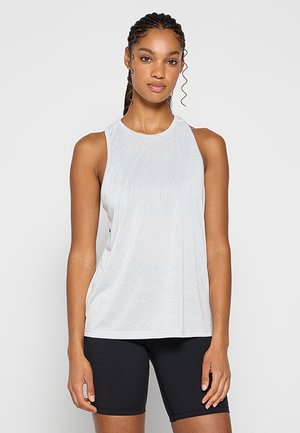 Jasnoszara, bezrękawnikowa koszulka sportowa z okrągłym dekoltem, o delikatnej teksturze i luźnym kroju. W połączeniu z czarnymi szortami rowerowymi.