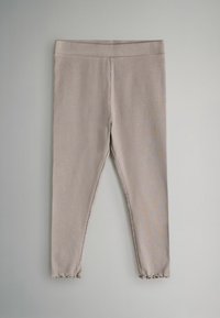 Leggings de canalé en color beige con una cintura elástica y dobladillo con ondas, que presentan una textura suave y una forma ajustada.