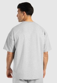 T-shirt grigio oversize con maniche corte, realizzata in un tessuto morbido. Presenta un colletto rotondo e nessuna grafica o motivo visibile.