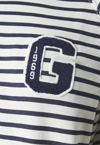 Randig skjorta i vitt och marinblått i bomull med en texturerad, broderad "G" och året "1969" nedanför.