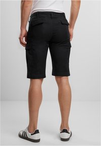 Shorts cargo noirs avec poches latérales, fabriqués dans un matériau robuste, présentant une coupe droite et une longueur jusqu'aux genoux.