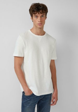 Witte kortemouwen blouse in een geweven stof met een ronde hals en subtiele details, gecombineerd met blauwe denim jeans.