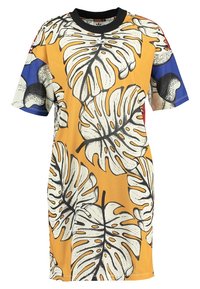 Sukienka T-shirt z dużym białym i czarnym nadrukiem liścia monstera na musztardowej żółci, z niebieskimi, czerwonymi i kremowymi rękawami w kolorowe bloki.