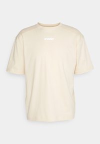 T-shirt in cotone beige con maniche corte, scollatura rotonda e un logo bianco stampato sul davanti. Design semplice, monocolore senza motivi.
