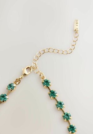 Bransoletka w kolorze złota z naprzemiennie ustawionymi zielonymi kamieniami szlachetnymi, każdy osadzony w pręcie, z zapięciem typu lobster i regulowanym łańcuszkiem.