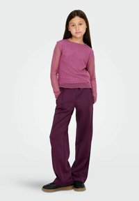 Purple long-sleeve top with sheer mesh sleeves and light embellishments; paired with loose, deep purple trousers and black shoes.