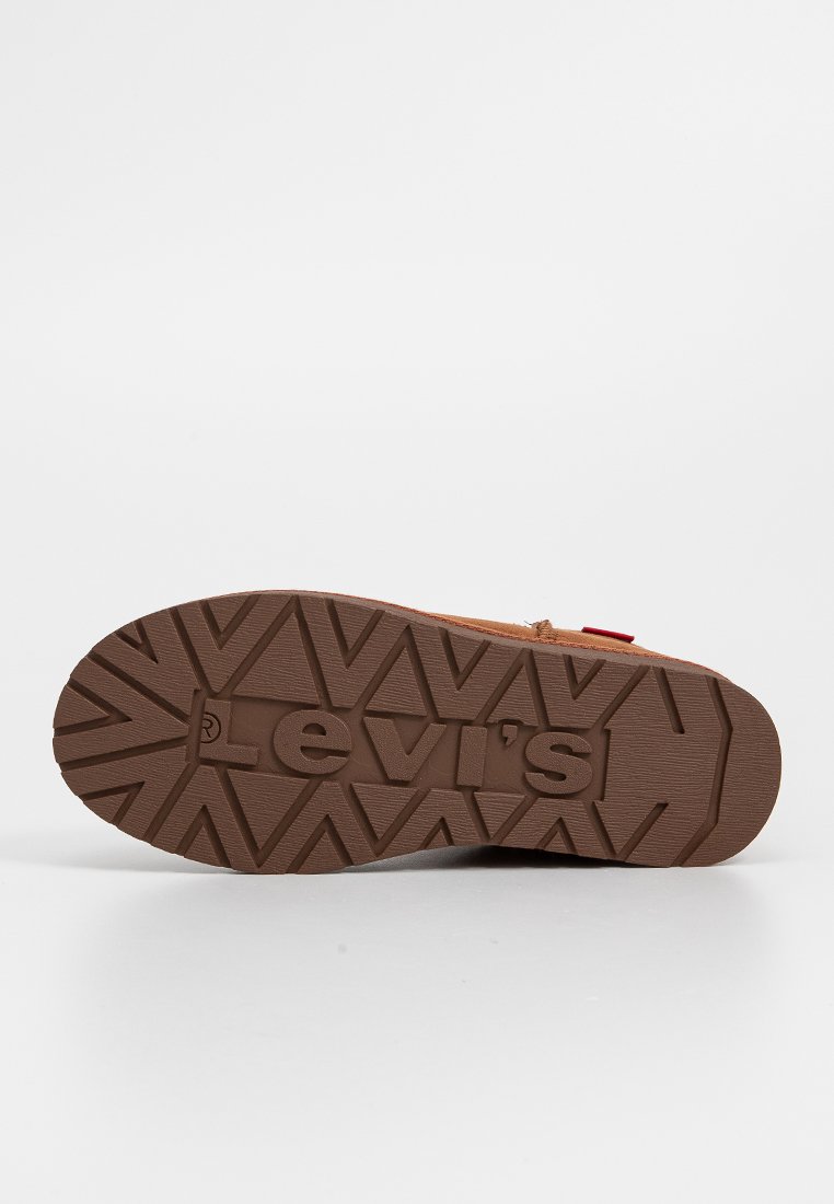 Brązowa podeszwa buta ma teksturowany wzór z trójkątnymi kształtami oraz wytłoczoną nazwą marki "Levi's" na środku.