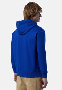 Felpa blu in cotone con cappuccio e polsini a coste. Presenta una texture liscia e una silhouette aderente, visibile dal retro.