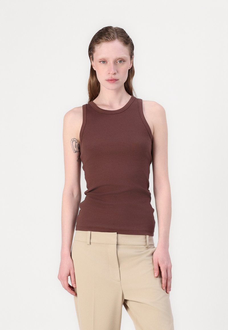 Brun tank topp med en tettsittende design, laget av glatt stoff, med rund halslinning og brede skulderstropper. Kombinert med beige bukser.