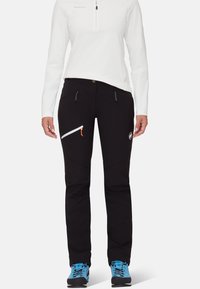 Svarta utomhusbyxor med slim fit, med två framfickor och en diagonalt placerad dragkedjeficka. Inkluderar en vit logotyp och oranga dragkedjeaccent.