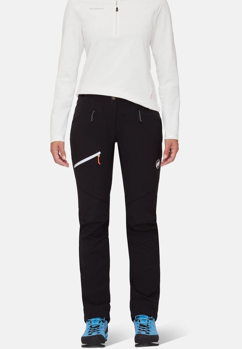 Svarta utomhusbyxor med slim fit, med två framfickor och en diagonalt placerad dragkedjeficka. Inkluderar en vit logotyp och oranga dragkedjeaccent.